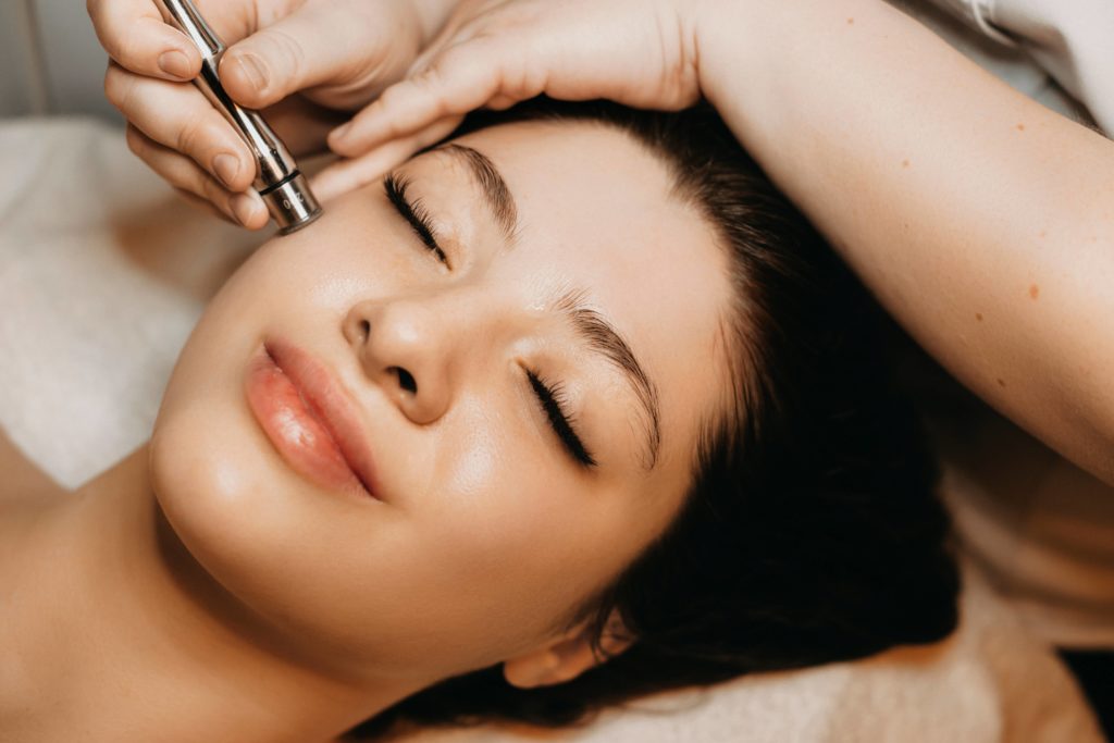 Close up portrait of blonde woman with cosmetologist hands giving SkinPen Microneedling | Beauty at First Sight Med Spa in Chicago, Illinois