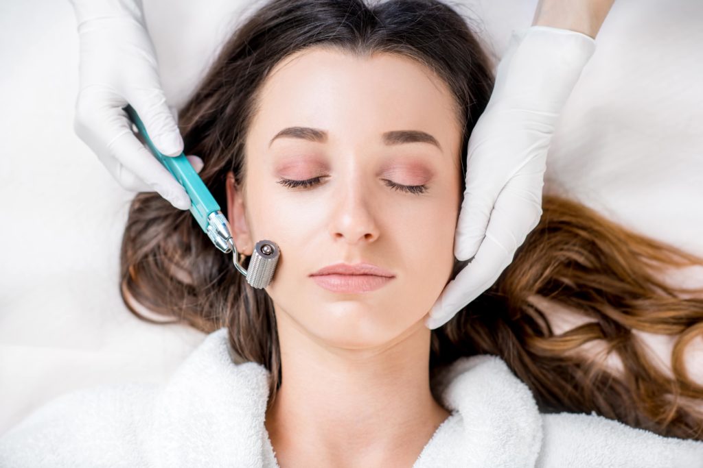 Young womens Face with closed eyes - MICRONEEDLING FOR ACNE SCARS Cosmetologist holding Dermaroller and woman's face in hands | Beauty at First Sight Med Spa in Chicago, Illinois